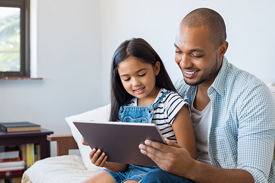 Young dad reading to his daughter on his tablet
